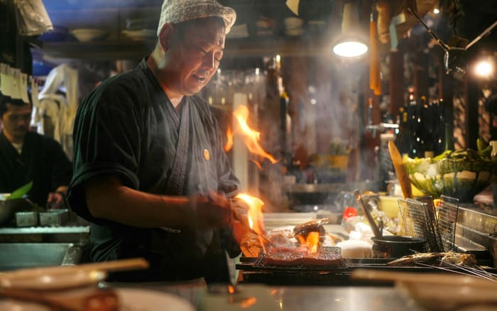 Chef working the flame on a live cooking line