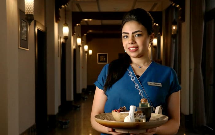 Hotel team member carrying an amenity tray along a guest corridor